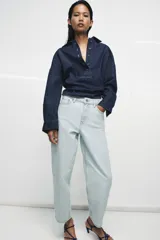 Jeans de tiro alto y silueta tapered, confeccionados en denim negro con costuras en tono contrastante. Cuenta con diseño de cinco bolsillos, trabillas para cinto y cierre frontal con cremallera y botón metálico.