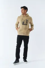 Buzo canguro color beige de felpa para hombre, con capucha ajustable, bolsillos y arte estampado.