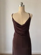 Vestido corto de microtul color marrón con diseño de doble capa, que incluye una base opaca y una capa exterior semitransparente. Presenta escote drapeado, tirantes finos y un ajuste ceñido al cuerpo con efecto fruncido lateral.