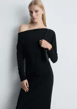 Vestido largo negro de diseño entallado con hombros descubiertos y manga larga. Presenta detalles fruncidos en el lateral y un corte recto.