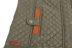 Chaleco beige capitoneado con cierre frontal y cuello de pana marrón.