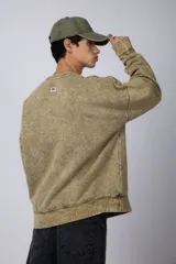 Buzo de cuello redondo con efecto de teñido artesanal acid wash. Presenta un corte oversize, mangas largas con puños acanalados y etiqueta pequeña en el puño izquierdo.
