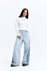 Jean de tiro alto con corte super oxford y silueta amplia. Presenta un diseño bicolor con paneles en diferentes tonos de azul y ruedo desflecado.