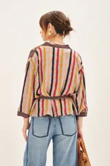 Kimono corto con mangas 3/4, confeccionado en viscosa estampada con diseño floral y rayas verticales. Presenta un cierre frontal cruzado con lazo ajustable en la cintura y forrería interior.