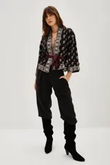 Kimono corto de estilo bohemio, confeccionado en viscosa negra con estampado paisley y detalles bordados en los bordes frontales y mangas. Presenta mangas tres cuartos y un lazo ajustable en la cintura con estampado animal print.