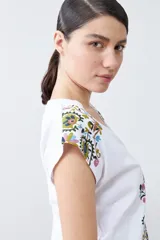 Remera blanca de algodón con escote en V y estampado floral en el frente y los hombros.