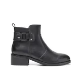 Bota corta de diseño urbano confeccionada en símil cuero liso, con punta redondeada y taco medio recto. Presenta un detalle lateral con tira, hebilla metálica y apliques decorativos, además de una tira trasera para facilitar el calce y cierre interno.