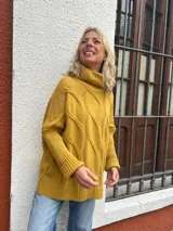 Polera de tejido de punto color amarillo mostaza, con diseño de ochos, cuello alto y corte oversize.