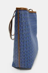 Bolso tipo tote de hombro con cuerpo estampado en tonos azules con patrón geométrico. Cuenta con detalles en tono tostado en las asas dobles, bordes y costuras en contraste. Cierre mediante botón imantado y compartimento interior.