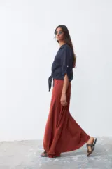 Camisa de lino color azul marino, con cuello clásico, cierre frontal de botones y mangas tres cuartos con trabilla. Presenta un diseño con nudo en la parte inferior delantera.