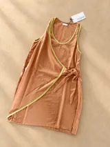 Vestido corto sin mangas de tusor color camel, con diseño cruzado tipo pareo, lazo lateral para atar y detalles de vivos en color verde lima en el escote y los bordes.