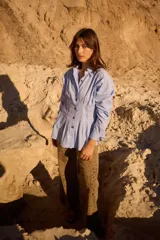 Camisa de silueta entallada con diseño tipo corset, destacada por alforzas verticales en la cintura que aportan estructura. Presenta cuello clásico, cierre frontal con botones y mangas largas con puños abotonados.