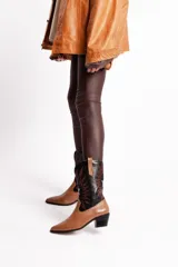 Bota tejana de cuero color marrón claro con puntera fina, caña media con bordados en negro y blanco, y taco bajo.