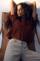 Blusa marrón de lyocell con escote redondo, mangas cortas abullonadas y cuerpo fruncido con detalle de tiras decorativas.