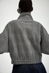Chaqueta estilo bomber con estampado de cuadros, cuello subido, manga larga y cierre frontal con cremallera. Presenta bolsillos delanteros y bajo elástico.