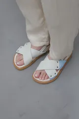Sandalias planas color celeste y blanco, con tiras anchas cruzadas y suela color caramelo.
