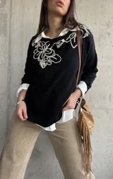 Sweater negro con diseño bordado en hilo crudo en el escote y el hombro, de manga larga y calce holgado.
