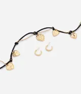 Conjunto de accesorios Accessories compuesto por un collar de cordón negro con cadena veneciana dorada y dijes colgantes en forma de corazón, acompañado de un par de caravanas de argolla doradas.