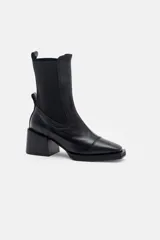 Bota tipo chelsea de cuero color bordó, con paneles elásticos laterales negros, puntera cuadrada y taco bloque negro.