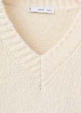 Jersey de punto grueso color blanco, con cuello en V, manga larga y diseño holgado.