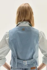 Chaleco de denim celeste con bordados decorativos en el frente, cierre de botones y corte entallado.