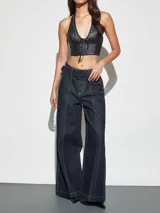 Jean azul oscuro de corte wide leg y tiro alto, con costuras pespunteadas verticales al frente y cinturón incorporado con hebilla cuadrada.