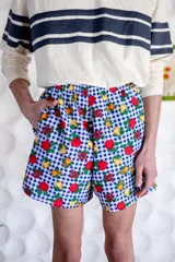 Short unisex de corte holgado con cintura elástica y estampado a cuadros rojos y blancos con dibujos de frutas.