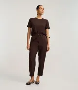 Pantalón de vestir femenino color marrón oscuro, de corte fluido y tiro medio/alto, con cintura elástica ajustable mediante cordón. Presenta bolsillos laterales y cierre frontal.