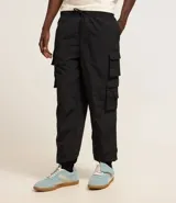 Pantalón jogger color beige, confeccionado en tejido plano de poliamida, con cintura elástica y cordón de ajuste. Presenta múltiples bolsillos cargo con solapa en los laterales y elástico en los puños.