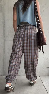 Pantalón babucha de corte holgado, con estampa de cuadros en tonos marrón y celeste, cintura elástica con cordón ajustable y puños fruncidos en los tobillos.