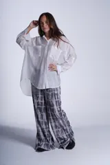 Camisa negra de tela traslúcida con cuello clásico, cierre frontal con botones y dos bolsillos de parche en el pecho.