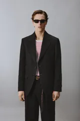 Blazer de corte regular confeccionado en lino, con solapas de muesca, cierre frontal de botones y múltiples bolsillos con solapa en la parte frontal. Presenta un diseño estructurado con abertura en la espalda y forro parcial.