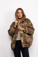 Campera tipo bomber con diseño floral estilo tapicería en tonos verdes, marrones y rosados. Presenta cuello camisero, cierre frontal con botones metálicos vintage, mangas largas con puños elásticos y ruedo con elástico.