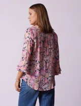 Blusa estampada con flores en tonos rosa, naranja y azul marino. Tiene escote en V con detalle de pliegues y mangas 3/4 con volados.