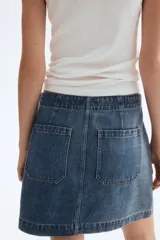 Pollera mini de denim color azul medio, tiro alto, con cordones cruzados en el frente y bolsillos delanteros tipo parche.