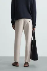 Pantalón chino de corte slim fit, confeccionado en tejido elástico. Presenta bolsillos frontales, bolsillos traseros de vivo con botón y cierre frontal con cremallera y botón.