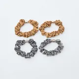 Pack de cuatro coleteros tipo scrunchie, dos en color bronce satinado y dos con estampado de piel de serpiente en tonos gris y negro. Cada uno cuenta con un detalle metálico central.