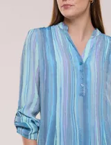 Blusa de gasa de la marca Zac & Rachel, con estampado de rayas verticales en tonos azules, celestes y lilas. Presenta cuello a la base con escote en V, abertura central con botones, detalle plisado en el frente y mangas de largo regulable con presilla y botón.
