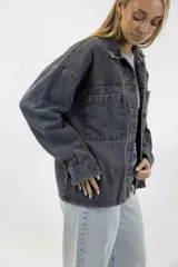 Camisa oversize de denim color gris oscuro, con cierre frontal de botones, bolsillos aplicados en el pecho y mangas largas.