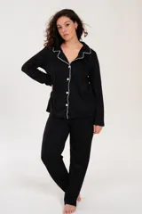 Pijama de dos piezas color negro con ribetes blancos, compuesto por una camisa de manga larga con botones y cuello tipo solapa, y un pantalón largo con cintura elástica.