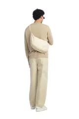Bolso de hombro de tejido color beige, con diseño tipo medialuna, asa larga y cierre de cremallera.