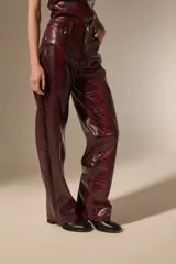 Pantalon de corte recto con diseño de estampado de piel de serpiente, confeccionado en cuero sintético (PU). Presenta bolsillos laterales y cierre frontal con botón.