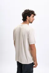 Remera de manga corta color beige claro, con cuello redondo y un pequeño estampado central en el pecho que dice "BUILT FOR THE CHILL".
