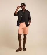 Bermuda de sarga color salmón, con trabillas en la cintura, cierre con botón y cremallera, y bolsillos laterales.