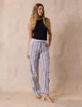 Pantalón de lino con rayas verticales en tonos beige, azul y gris. Tiene pretina elastizada, bolsillos inclinados en la parte delantera y un bolsillo tipo cargo en el lateral. Marca Zac & Rachel.
