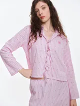 Camisa de dormir de popelina de algodón, con diseño de rayas verticales y pequeños motivos bordados. Presenta cierre frontal mediante lazos ajustables, cuello camisero y mangas largas.