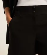 Short sastre color tostado, de corte recto y tiro medio, con bolsillos laterales y cierre frontal oculto.