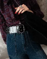 Faja ancha de cuero negro con tachas metálicas circulares distribuidas por toda la superficie y hebilla cuadrada grande de metal plateado.