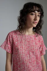 Blusa estampada fucsia y beige con cuello redondo y mangas cortas con volados.