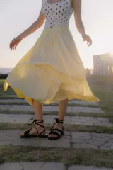 Sandalias negras de cuero con suela plana y tiras finas para atar alrededor del tobillo.